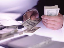 A man lays cash notes on a table (http://www.bbc.co.uk/schools/gcsebitesize/business/images/investor.jpg)